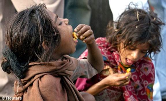 Street children eat bread on a roadside in Delhi, India's capital
